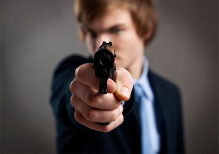 simsearch:400-08551381,k - Stressed businessman holding and pointing a gun to the camera Fotografie stock - Microstock e Abbonamento, Codice: 400-07897667