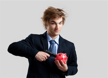 simsearch:400-05715051,k - Man holding a piggy bank and shooting with a gun Fotografie stock - Microstock e Abbonamento, Codice: 400-07898740