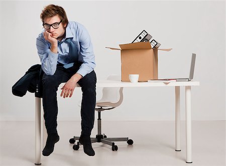 Young man sitting on the desk after being fired Stock Photo - Budget Royalty-Free & Subscription, Code: 400-07898776