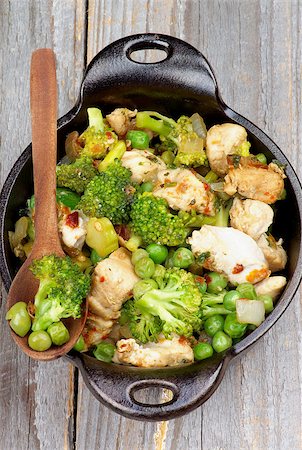 simsearch:400-07481067,k - Homemade Chicken Stew with Broccoli, Bell Pepper and Green Pea in Black Saucepan with Wooden Spoon isolated on Rustic Wooden background. Top View Stock Photo - Budget Royalty-Free & Subscription, Code: 400-07899026