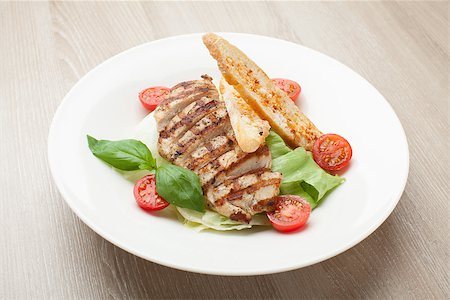 Gourmet delicious caesar salad with grilled beef meat fillet, romaine lettuce, cherry tomatoes,  cheese croutons and basil served in white plate Stock Photo - Budget Royalty-Free & Subscription, Code: 400-07899768