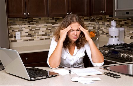 simsearch:6109-07601399,k - stressed woman looking at bills while sitting in the kitchen Photographie de stock - Aubaine LD & Abonnement, Code: 400-07893291