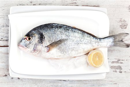 simsearch:400-07776969,k - Fresh fish on white plate with lemon on white textured wooden background, top view. Culinary seafood concept. Foto de stock - Super Valor sin royalties y Suscripción, Código: 400-07893671