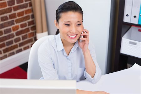 simsearch:614-02003461,k - Smiling female executive using mobile phone at office desk Stock Photo - Budget Royalty-Free & Subscription, Code: 400-07900407