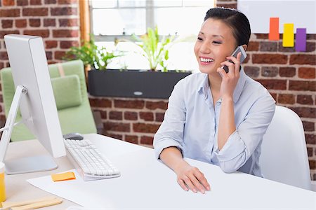 simsearch:614-02003461,k - Smiling female executive using mobile phone at office desk Stock Photo - Budget Royalty-Free & Subscription, Code: 400-07900408