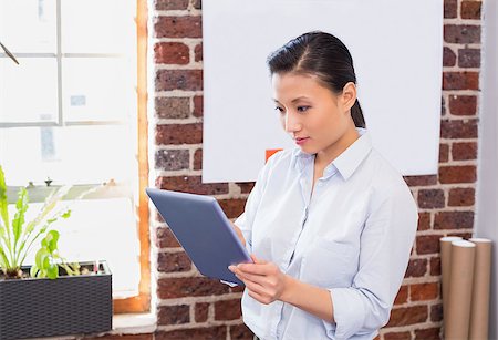 people stand in front brick wall - Concentrated young businesswoman using digital tablet in the office Photographie de stock - Aubaine LD & Abonnement, Code: 400-07900413