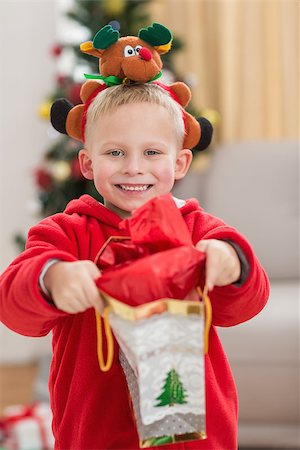 simsearch:400-07902186,k - Festive little boy smiling at camera with gift at home in the living room Foto de stock - Super Valor sin royalties y Suscripción, Código: 400-07902142