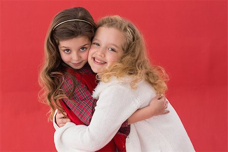 simsearch:400-05352235,k - Festive little girls hugging and smiling on red background Photographie de stock - Aubaine LD & Abonnement, Code: 400-07902196