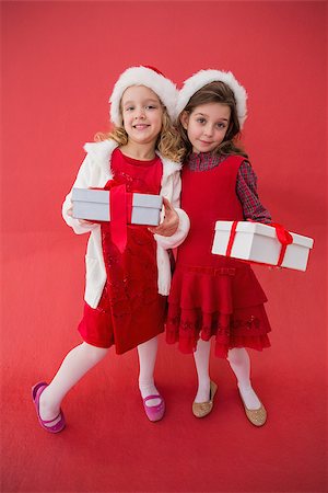 simsearch:400-05352235,k - Festive little girls smiling at camera with gifts on red background Photographie de stock - Aubaine LD & Abonnement, Code: 400-07902200