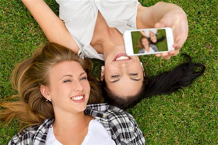 simsearch:400-07303759,k - Female best friends lying on the grass and taking selfies Stockbilder - Microstock & Abonnement, Bildnummer: 400-07903144