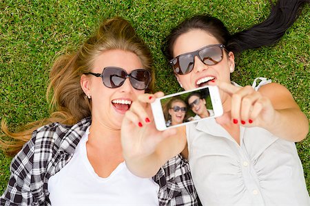simsearch:400-07303759,k - Female best friends lying on the grass and taking selfies Stockbilder - Microstock & Abonnement, Bildnummer: 400-07903146