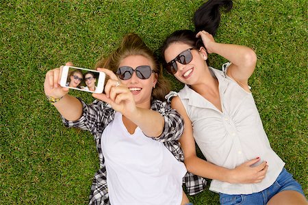 simsearch:400-07303759,k - Female best friends lying on the grass and taking selfies Stockbilder - Microstock & Abonnement, Bildnummer: 400-07903148