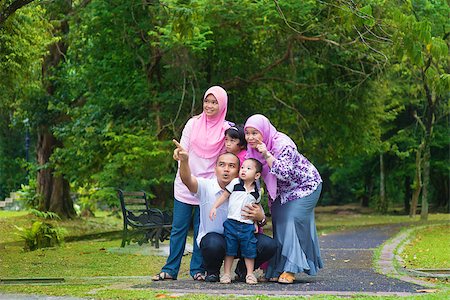 Happy Southeast Asian family outdoor lifestyle at nature green park, pointing and looking away. Stock Photo - Budget Royalty-Free & Subscription, Code: 400-07915153