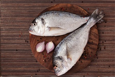 simsearch:400-07776969,k - Two fresh sea bream with colorful peppercorn and onion on round wooden chopping board on brown background. Natural seafood background in brown, top view. Foto de stock - Super Valor sin royalties y Suscripción, Código: 400-07915698
