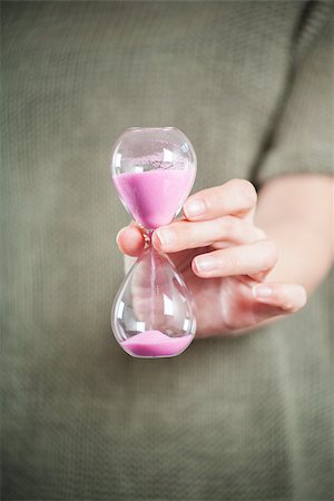 pink sand clock in woman hands over green background Fotografie stock - Microstock e Abbonamento, Codice: 400-07916165