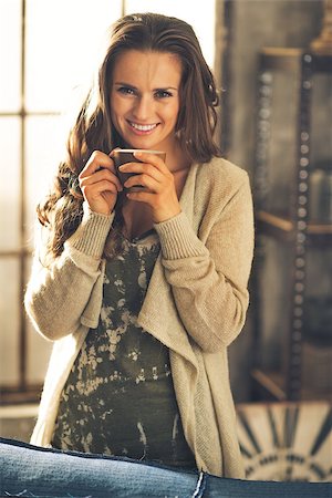 Portrait of smiling young woman with cup of coffee in loft apartment Stockbilder - Microstock & Abonnement, Bildnummer: 400-07916446