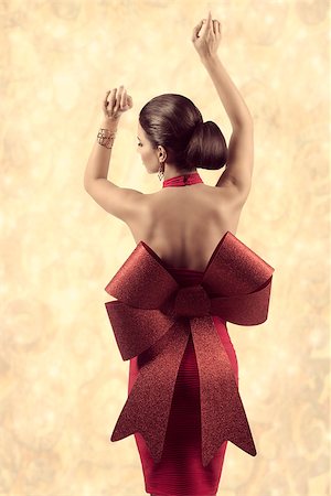 sensual brunette woman with perfect body wearing sexy red christmas dress with big glitter bow and golden jewellery, in fashion pose turned on her naked back Stock Photo - Budget Royalty-Free & Subscription, Code: 400-07918511