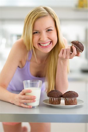 Happy teenager girl eating muffin with milk in kitchen Stock Photo - Budget Royalty-Free & Subscription, Code: 400-07919092