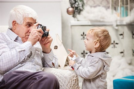 Senior man taking photo of his toddler grandson at Christmas time Stock Photo - Budget Royalty-Free & Subscription, Code: 400-07924654