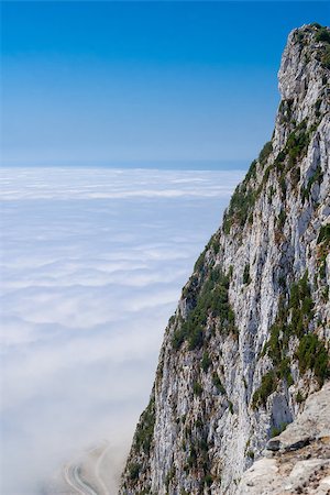 Gibraltar cliff face above clouds with road below against clear blue sky. Fotografie stock - Microstock e Abbonamento, Codice: 400-07925627