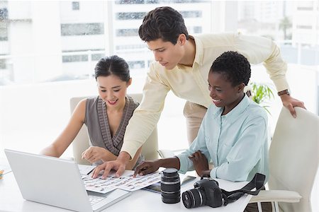 simsearch:400-07926810,k - Casual business team looking at laptop together in creative office Fotografie stock - Microstock e Abbonamento, Codice: 400-07926208