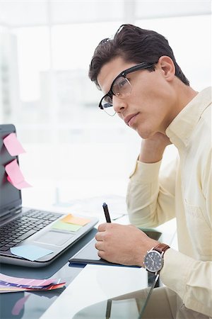 simsearch:400-07926750,k - Designer with glasses thinking and using digitizer in his office Stock Photo - Budget Royalty-Free & Subscription, Code: 400-07926814