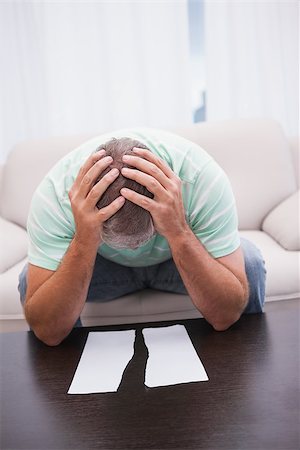 simsearch:400-07333928,k - Worried man looking at ripped page at home in the living room Stock Photo - Budget Royalty-Free & Subscription, Code: 400-07927817