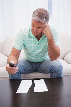 simsearch:400-07333928,k - Worried man looking at ripped page sending a text at home in the living room Stock Photo - Budget Royalty-Free & Subscription, Code: 400-07927818