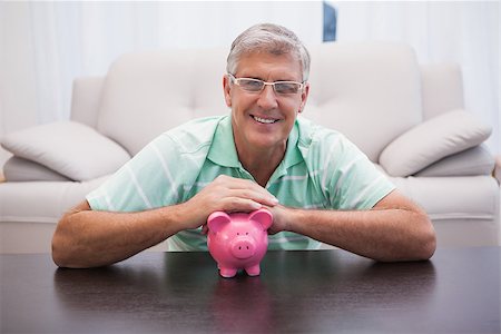 simsearch:400-07333928,k - Smiling mature man with piggy bank at home in the living room Stock Photo - Budget Royalty-Free & Subscription, Code: 400-07927819
