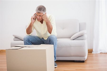 simsearch:400-07928013,k - Man talking on phone looking at box at home in the living room Fotografie stock - Microstock e Abbonamento, Codice: 400-07927841