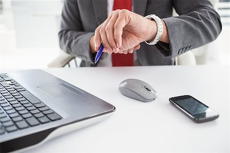 Mature businessman checking the time in his office Stock Photo - Budget Royalty-Free & Subscription, Code: 400-07927901