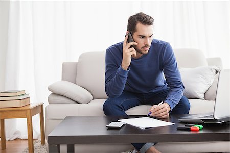 simsearch:400-07333928,k - Young man paying his bills with laptop at home in the living room Stock Photo - Budget Royalty-Free & Subscription, Code: 400-07927936