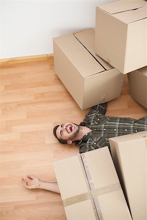 falling with box - Man lying under fallen boxes at home in the living room Foto de stock - Super Valor sin royalties y Suscripción, Código: 400-07928011