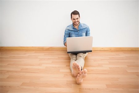 simsearch:400-07931092,k - Casual man sitting on floor using laptop at home in the living room Foto de stock - Super Valor sin royalties y Suscripción, Código: 400-07928024