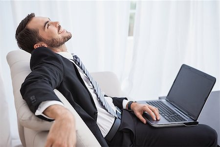 simsearch:400-07274613,k - Smiling businessman using laptop on his couch at home in the living room Stock Photo - Budget Royalty-Free & Subscription, Code: 400-07928053