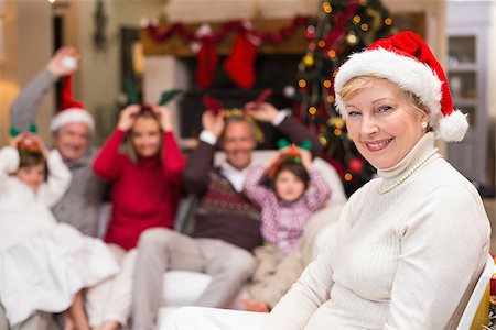 simsearch:400-06871557,k - Smiling grandmother in santa hat with her family behind at home in the living room Photographie de stock - Aubaine LD & Abonnement, Code: 400-07928179