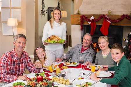 simsearch:400-06871551,k - Woman holding turkey roast with family at dining table at home in the living room Stock Photo - Budget Royalty-Free & Subscription, Code: 400-07928253