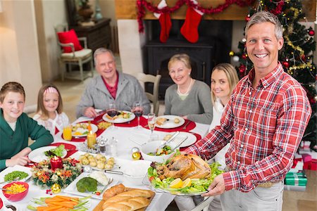 simsearch:400-06871551,k - Man holding turkey roast with family at dining table at home in the living room Stock Photo - Budget Royalty-Free & Subscription, Code: 400-07928260