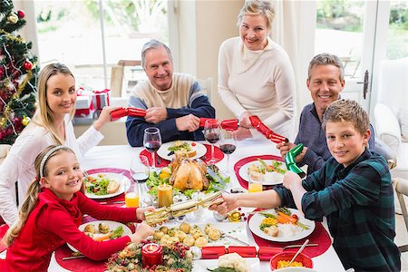 simsearch:400-06871557,k - Family pulling christmas crackers at the dinner table at home in the living room Photographie de stock - Aubaine LD & Abonnement, Code: 400-07928304