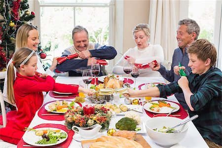 simsearch:400-06871557,k - Family pulling christmas crackers at the dinner table at home in the living room Photographie de stock - Aubaine LD & Abonnement, Code: 400-07928305