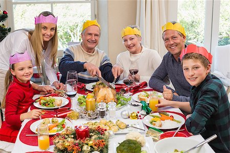 simsearch:400-06871557,k - Grandfather in party hat carving chicken during dinner at home in the living room Photographie de stock - Aubaine LD & Abonnement, Code: 400-07928319