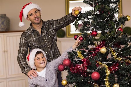 decorating small xmas tree - Smiling son and dad decorating the christmas tree at home in the living room Stock Photo - Budget Royalty-Free & Subscription, Code: 400-07928735