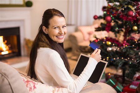 simsearch:400-07474252,k - Smiling brunette shopping online with laptop at christmas at home in the living room Stock Photo - Budget Royalty-Free & Subscription, Code: 400-07928753