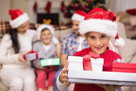 simsearch:400-06930138,k - Festive daughter holding pile of gifts with his family behind  at home in the Stock Photo - Budget Royalty-Free & Subscription, Code: 400-07928766