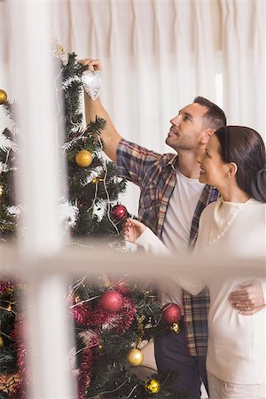 simsearch:400-07931092,k - Love couple decorating the christmas tree together at home in the living room Foto de stock - Super Valor sin royalties y Suscripción, Código: 400-07928814