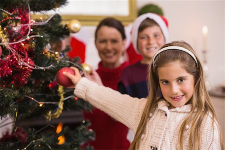 decorating small xmas tree - Smiling little girl decorating the christmas tree at home in the living room Stock Photo - Budget Royalty-Free & Subscription, Code: 400-07928894