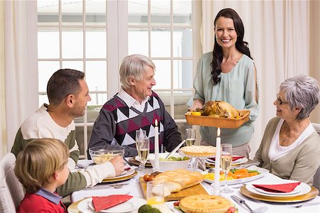 simsearch:400-07928326,k - Woman holding turkey roast with family at dining table at home in the living room Photographie de stock - Aubaine LD & Abonnement, Code: 400-07928910