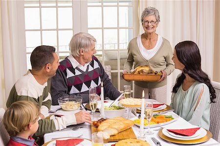 simsearch:400-06871551,k - Grandmother holding turkey roast with family at dining table at home in the living room Stock Photo - Budget Royalty-Free & Subscription, Code: 400-07928912