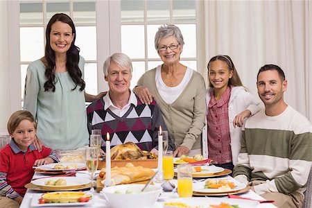 simsearch:400-07928326,k - Happy extended family at christmas dinner posing at camera at home in the living room Photographie de stock - Aubaine LD & Abonnement, Code: 400-07928957