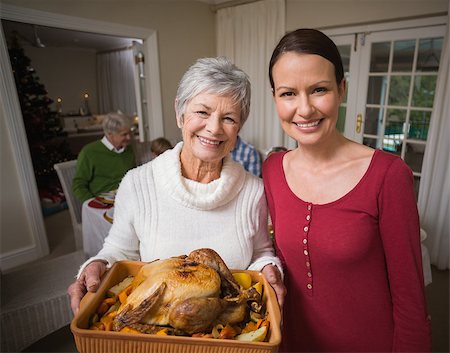simsearch:400-07928327,k - Women posing with roast turkey in front of their family at home in the living room Foto de stock - Super Valor sin royalties y Suscripción, Código: 400-07929032